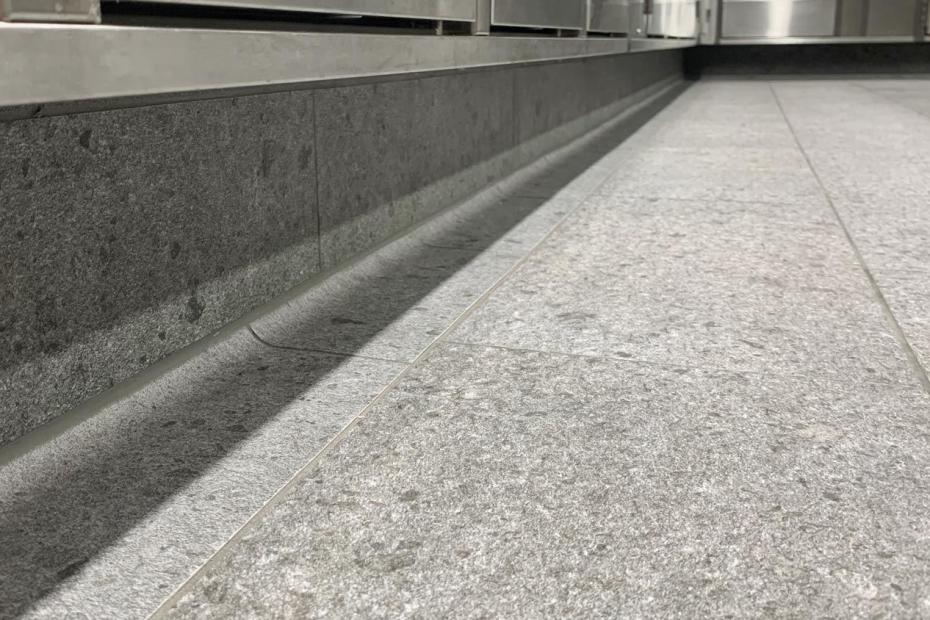 Besonders im Fokus steht hier der Großküchenboden, weil er im Alltag einer Vielzahl von Belastungen ausgesetzt ist. Die liegend verlegte Sockelfliese (unten) sorgt für einen sicheren Übergang zur Wand.